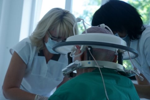 Пациент в шлеме готовится к проведению лечения